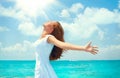 Beautiful happy young woman in white dress on tropical resort island. Vacation Concept. Beautiful girl on the ocean beach raising