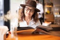 Beautiful hapy mature senior woman in glasses and hat looking at menu in cafe