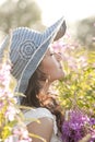 Beautiful, healthy, sensual, sexy, young Asian woman enjoying summer sunlight in a flower garden. She is wearing a sun hat.