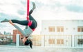 Beautiful healthy strong woman wearing sport bra, relaxing, exercise yoga fly in air, aerial hoop on outdoor rooftop in morning. Royalty Free Stock Photo