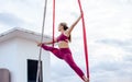 Beautiful healthy strong woman wearing sport bra, relaxing, exercise yoga fly in air, aerial hoop on outdoor rooftop in morning. Royalty Free Stock Photo