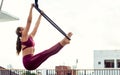 Beautiful healthy strong woman wearing sport bra, relaxing, exercise yoga fly in air, aerial hoop on outdoor rooftop in morning. Royalty Free Stock Photo