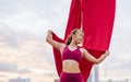 Beautiful healthy strong woman wearing sport bra, relaxing, exercise yoga fly in air, aerial hoop on outdoor rooftop in morning. Royalty Free Stock Photo