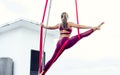 Beautiful healthy strong woman wearing sport bra, relaxing, exercise yoga fly in air, aerial hoop on outdoor rooftop in morning. Royalty Free Stock Photo