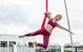 Beautiful healthy strong woman wearing sport bra, relaxing, exercise yoga fly in air, aerial hoop on outdoor rooftop in morning. Royalty Free Stock Photo