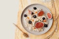 Beautiful healthy vegan Breakfast, cereal porridge, blueberries, fresh figs and sea buckthorn on yellow cotton napkin, honey stick