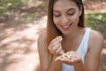 Beautiful healthy woman eating pistachio seeds outdoor. Looks at pistachios in her hand