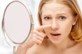 Beautiful healthy woman frightened saw in the mirror acne and wrinkles