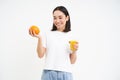 Beautiful and healthy young woman, starts her day with fresh juice, holding orange fruit and smiling, white background Royalty Free Stock Photo