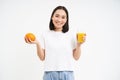 Beautiful and healthy young woman, starts her day with fresh juice, holding orange fruit and smiling, white background Royalty Free Stock Photo