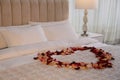 Beautiful heart of rose petals on bed in room Royalty Free Stock Photo