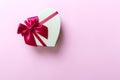 Beautiful heart shaped gift box with red silk bow on a pink background Royalty Free Stock Photo