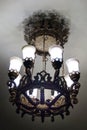 A beautiful heavy large metal wrought-iron lamp with white matte lampshades in the Moscow metro