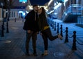 Beautiful heterosexual couple is on the path of cobblestones and kiss. On the background of a city street