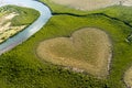 Beautiful high angle shot of a green field with a  heart shape and a river on the left Royalty Free Stock Photo