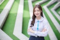 Beautiful high school Asian student girl in the school uniform stands and smiles happily with braces on her teeth while she arm Royalty Free Stock Photo