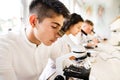 Beautiful high school students with microscopes in laboratory. Royalty Free Stock Photo