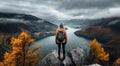 Beautiful hiker girl at the top of the mountain with breathtaking view of a lake rocks and autumn colored trees