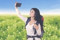 Beautiful hiker woman taking picture on meadow