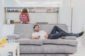 Beautiful hilarious young man holding a remote control. During this, the TV is watching while sitting on the couch at