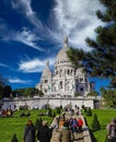 Beautiful hill on sunny autmn day with people relaxing, Sacre Coeur church, clear blue sky, fluffy white cloud, green lawn