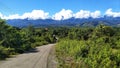 beautiful hilltop road dotted with shrubs and a beautiful mountain foreground