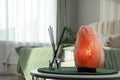 Beautiful Himalayan salt lamp and air reed freshener on table, space for text