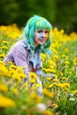 Beautiful hipster alternative young woman with green hair sits in grass with dandelion in park Royalty Free Stock Photo