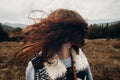 beautiful hipster traveler having fun in windy mountains, playing with hair. stylish woman hiking. wanderlust and travel concept