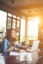 Beautiful hipster woman using laptop at cafe while drinking coffee, Relaxing holiday concept. Royalty Free Stock Photo