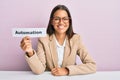 Beautiful hispanic business woman holding automation word on paper looking positive and happy standing and smiling with a