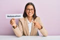 Beautiful hispanic business woman holding automation word on paper smiling happy pointing with hand and finger Royalty Free Stock Photo