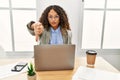 Beautiful hispanic business woman sitting on desk at office working with laptop looking unhappy and angry showing rejection and Royalty Free Stock Photo