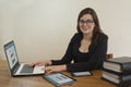 Beautiful Hispanic female office worker with glasses happy sitting at her desk working in front of her computer Royalty Free Stock Photo