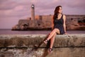 Beautiful hispanic girl sitting on the Malecon seawall at sunset in Havana Royalty Free Stock Photo