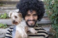 Beautiful Hispanic man with curly hairstyle holding Yorkshire terrier dog Royalty Free Stock Photo