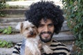 Beautiful Hispanic man with curly hairstyle holding Yorkshire terrier dog Royalty Free Stock Photo