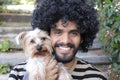 Beautiful Hispanic man with curly hairstyle holding Yorkshire terrier dog Royalty Free Stock Photo