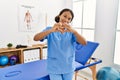 Beautiful hispanic physiotherapist woman at pain recovery clinic smiling in love doing heart symbol shape with hands Royalty Free Stock Photo