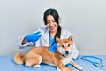 Beautiful hispanic veterinarian woman putting vaccine to puppy dog smiling and laughing hard out loud because funny crazy joke Royalty Free Stock Photo