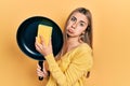 Beautiful hispanic woman cleaning cooking pan with scourer depressed and worry for distress, crying angry and afraid