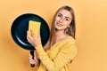 Beautiful hispanic woman cleaning cooking pan with scourer relaxed with serious expression on face