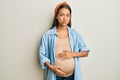 Beautiful hispanic woman expecting a baby, touching pregnant belly puffing cheeks with funny face Royalty Free Stock Photo