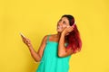 Beautiful Hispanic woman with  listening music on yellow background Royalty Free Stock Photo