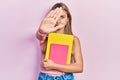 Beautiful hispanic woman holding books with open hand doing stop sign with serious and confident expression, defense gesture Royalty Free Stock Photo