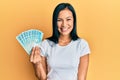 Beautiful hispanic woman holding 100 brazilian real banknotes looking positive and happy standing and smiling with a confident Royalty Free Stock Photo