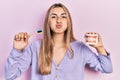 Beautiful hispanic woman holding denture and toothbrush puffing cheeks with funny face Royalty Free Stock Photo