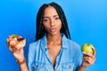 Beautiful hispanic woman holding pastry and healthy green apple looking at the camera blowing a kiss being lovely and sexy Royalty Free Stock Photo