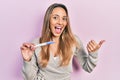 Beautiful hispanic woman holding pregnancy test result pointing thumb up to the side smiling happy with open mouth Royalty Free Stock Photo