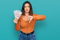 Beautiful hispanic woman holding russian 500 ruble banknotes with angry face, negative sign showing dislike with thumbs down, Royalty Free Stock Photo